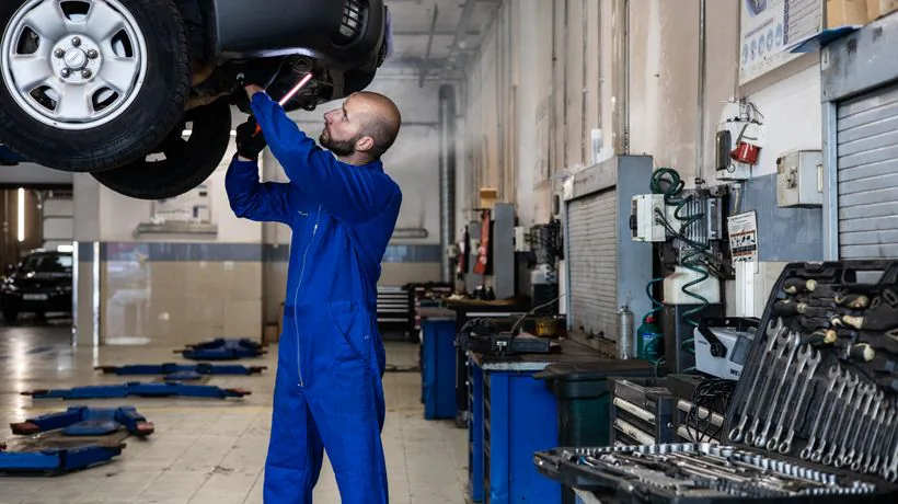 A mechanic inspecting a car, similar to an MOT check